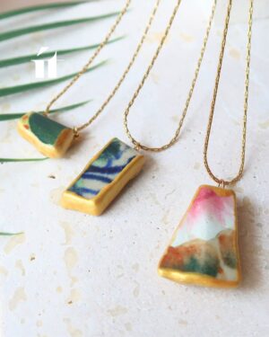 Three Kintsugi necklaces from the Kakera collection made with Song Be pottery shards, resin, and gold leaf